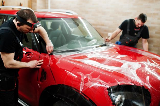 Technician carefully cleaning and inspecting Paint Protection Film on a luxury car at Premium Car Hub Dubai